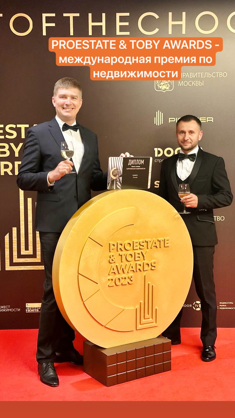 Команда Про.рент с дипломом премии у эмблемы PROESTATE & TOBY Awards 2023